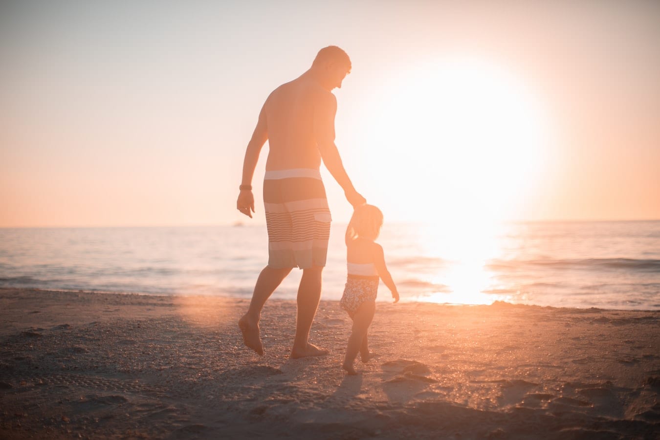 Father and child holding hands on the beach
