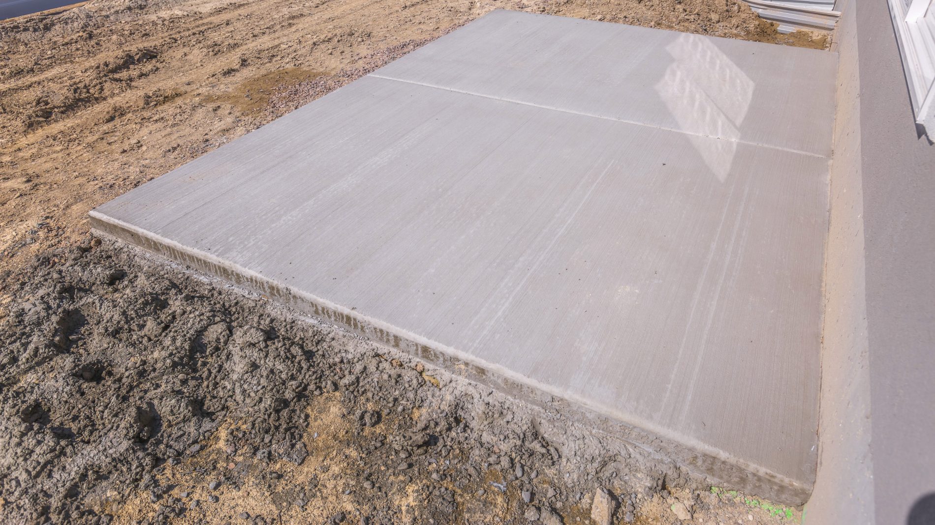 Flat horizontal concrete surface soil at a home under construction. Construction work at the yard of a a new house with no landscaping.